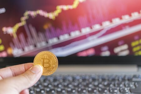 Bitcoin gold coin and defocused chart background. Virtual cryptocurrency concept. Bitcoin is a gold coin and a defocused graphics background. Bitcoin currency with blockchain concept.の写真素材