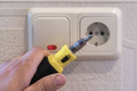 Hand Of An Electrician To Repair A Wall Socket. Closeup of man electrician's hand repairing an...