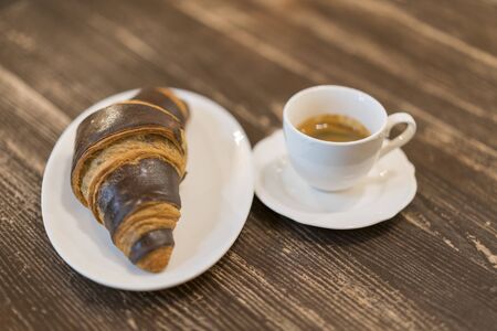 Coffee cup and fresh baked croissants on wooden background. Fresh and tasty croissants with...