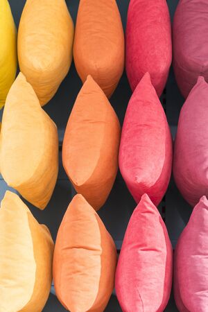 Multi-colored pillows background. Creative background made of pillows. Pink red yellow and beige pillows. vacation concept. Vertical photo.の写真素材