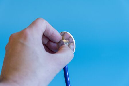 Doctor's hand with a stethoscope on a blue background. Concept of medicine and health check.の写真素材