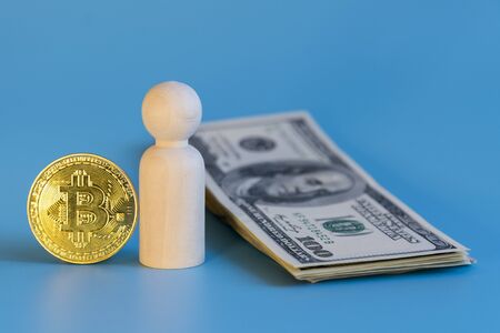 Figurine of a man of dollars and bitcoin on a blue background. Business concept choice between dollars and cryptocurrencyの写真素材