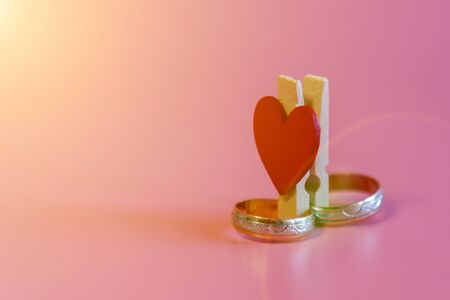 Wedding rings with a heart on a pink background. Love and marriage concept. Close up and top view of...