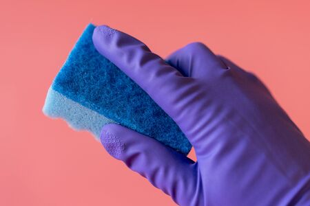 gloved hand with washcloth on pink background. Rubber gloves and a washcloth for cleaning on a pink...