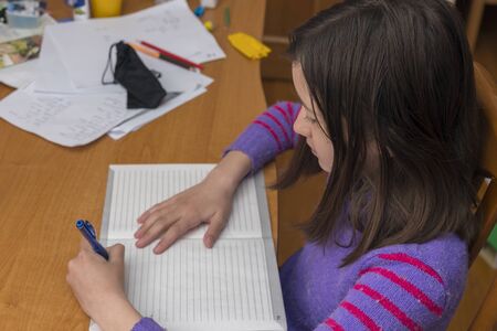 Home schooling. schoolgirl studying homework math during her online lesson at home, social distance during quarantine, self-isolation, online education concept, home schooler. tonedの写真素材