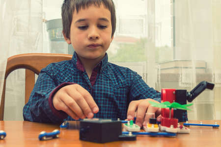 The boy playing an electric constructor. The child is played by intellectual toys. A boy in a blue shirt masters electronics. The concept of early development of children. tonedの写真素材