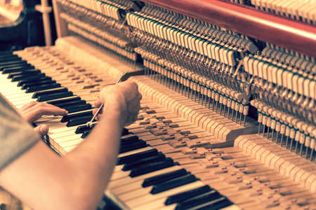 Piano tuning process. closeup of hand and tools of tuner working on grand piano. Detailed view of Upright Piano during a tuning. toned.の写真素材