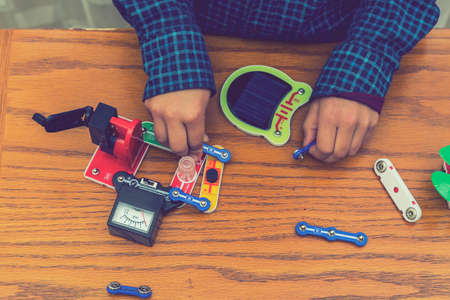 The boy playing an electric constructor. The child is played by intellectual toys. A boy in a blue shirt masters electronics. The concept of early development of children. tonedの写真素材