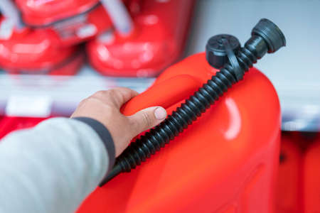 Red canister in the hands of a man. Concept of empty tank, problems with gasoline or diesel, refueling a carの写真素材