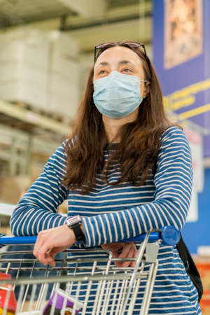 Asian young woman wearing a hygiene protective mask over her face while walking at the crowded shopping mall. influenza in crowded place. woman wearing a mask in the supermarketの写真素材