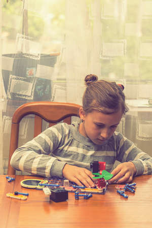 Close up kid hands creating toy from constructor. Toys of future concept. Education, children, technology, science and futuristic concept. E-learning. toned. verical photo. tonedの写真素材