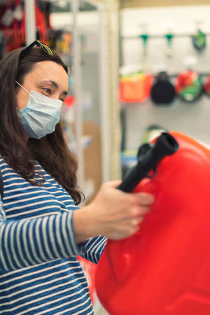 Woman in protective mask in a store with a canister. pandemic concept. Pandemic Shopping. toned. vertical photoの写真素材