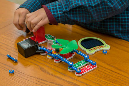 The boy playing an electric constructor. The child is played by intellectual toys. A boy in a blue shirt masters electronics. The concept of early development of childrenの写真素材
