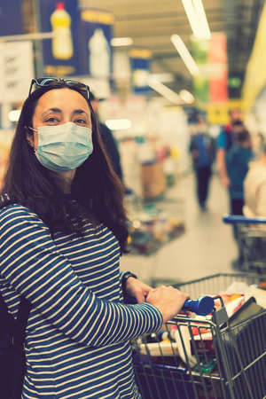 Asian young woman wearing a hygiene protective mask over her face while walking at the crowded shopping mall. Covid19 influenza in crowded place. woman wearing a mask in the supermarket. tonedの写真素材
