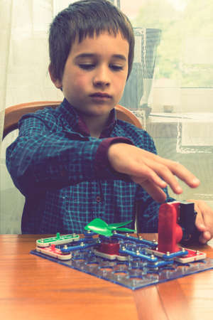 The boy playing an electric constructor. The child is played by intellectual toys. A boy in a blue shirt masters electronics. The concept of early development of children. vertical photoの写真素材