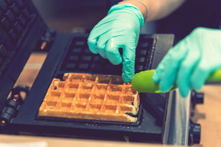 Waffle iron in the kitchen. Preparing homemade waffles, pouring a dough. Preparing of homemade waffles in twin waffle maker machine. Selective focus. tonedの写真素材
