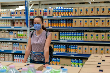 Alarmed female wears medical mask against virus while grocery shopping in supermarket or store- health, safety and pandemic conceptの写真素材