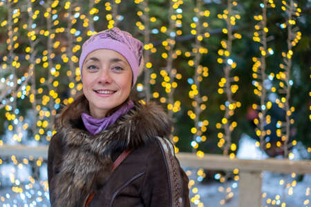 smiling young woman wearing winter clothes celebrating Christmas at the street with sparklersの写真素材