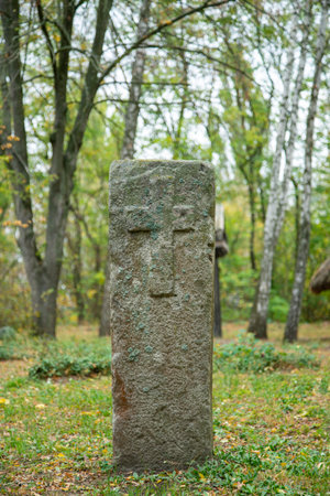 A worn sandstone grave marker in the shade on a very bright day. There is no text visible on the stone, but there is some moss on the top. Tombstone and graves in an ancient church graveyard. tonedの写真素材