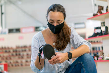 woman wearing face protective medical mask for protection from virus disease in shoes store during...