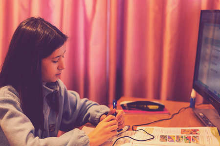 Smart preteen schoolgirl doing her homework with digital tablet at home. Child using gadgets to study. Education and learning for kids. Homeschooling during quarantine. toned. selected focusの写真素材
