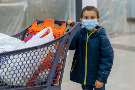 Boy wears protected mask in store. Shopping time during outbreak. Boy in a medical mask. Shopping with kids during virus outbreak. Boy in face mask in supermarket.の写真素材
