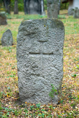 A worn sandstone grave marker in the shade on a very bright day. There is no text visible on the stone, but there is some moss on the top. Tombstone and graves in an ancient church graveyard. tonedの写真素材