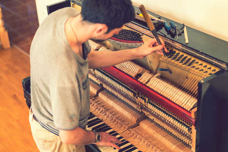 Piano tuning process. closeup of hand and tools of tuner working on grand piano. Detailed view of Upright Piano during a tuning. tonedの写真素材