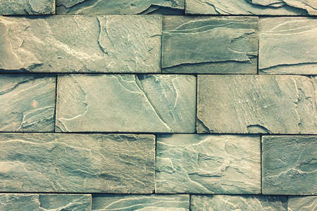 Stacked stone wall, natural stone cladding. Stone wall for background,Slab stone wall texture. Wall background of volcanic andesite basalt stone texture. tonedの写真素材