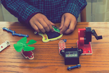 The boy playing an electric constructor. The child is played by intellectual toys. A boy in a blue shirt masters electronics. The concept of early development of children. tonedの写真素材