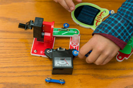 The boy playing an electric constructor. The child is played by intellectual toys. A boy in a blue shirt masters electronics. The concept of early development of children.の写真素材