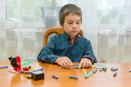 The boy playing an electric constructor. The child is played by intellectual toys. A boy in a blue shirt masters electronics. The concept of early development of children. tonedの写真素材
