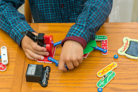 The boy playing an electric constructor. The child is played by intellectual toys. A boy in a blue shirt masters electronics. The concept of early development of childrenの写真素材
