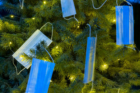 Horizontal color image with a front view of a Christmas tree decorated with blue masks. Celebrating new 2021 year during  pandemicの写真素材