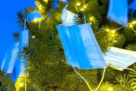 Christmas tree decorated with medical disposable medical masks. Celebrating new 2021 year during pandemicの写真素材