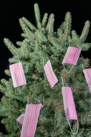 Christmas tree decorated with medical disposable medical masks. Celebrating new 2021 year during pandemic. vertical photoの写真素材