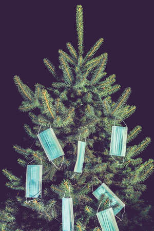 Christmas tree decorated with medical disposable medical masks. Celebrating new 2021 year during  pandemic. vertical photo. tonedの写真素材