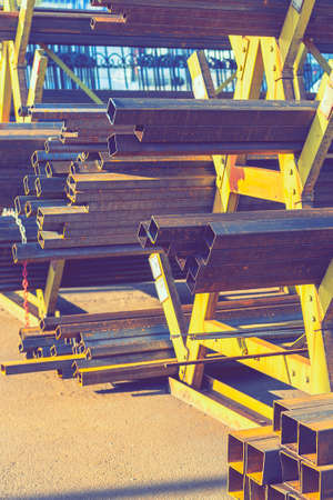 stack of steel pipe and metal beams on rack. metal pipes, profiles, rods, corners, rails, a choice of metal products. vertical photo. tonedの写真素材