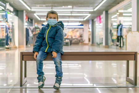 Toddler child, boy, wearing protective medical mask in shopping center during pandemic. The child wears a protective mask in the storeの写真素材