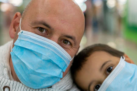 father and son with protective masks at home, protect infection from virus  on table, the new normal social distancing concept. close-upの写真素材