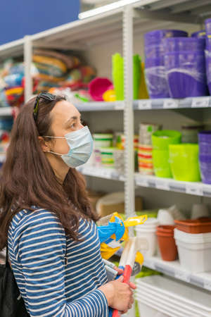 Woman in medical mask choosing goods in a store. Concept of shopping during quarantineの写真素材