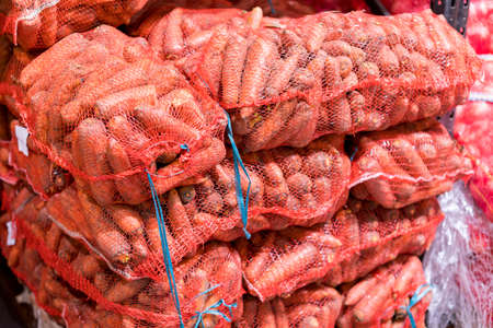 Carrot bags are packed and put up for sale in the market. Bags with Carrot. Carrots in bags close-up, a lot of Carrotes, a store or marketの写真素材