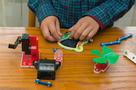 The boy playing an electric constructor. The child is played by intellectual toys. A boy in a blue shirt masters electronics. The concept of early development of childrenの写真素材