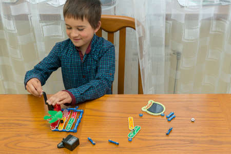 The boy playing an electric constructor. The child is played by intellectual toys. A boy in a blue shirt masters electronics. The concept of early development of childrenの写真素材