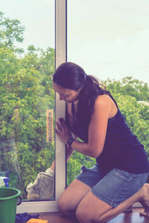 Attractive Woman Washing the Window. Cleaning Company worker working. Beautiful young woman is using a rag while cleaning windows. tonedの写真素材