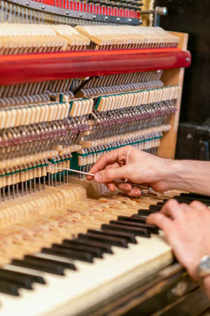 Setting up an old piano. The master repairs an old piano. Deep cleaning the piano. Hands of professional worker repairing and tuning an old piano. tonedの写真素材