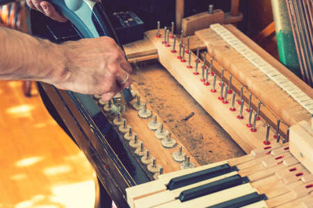Setting up an old piano. The master repairs an old piano. Deep cleaning the piano. Hands of professional worker repairing and tuning an old piano. tonedの写真素材
