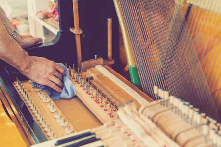 Setting up an old piano. The master repairs an old piano. Deep cleaning the piano. Hands of professional worker repairing and tuning an old piano. tonedの写真素材