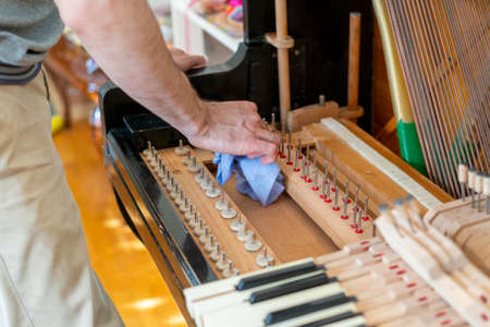 Setting up an old piano. The master repairs an old piano. Deep cleaning the piano. Hands of professional worker repairing and tuning an old piano. tonedの写真素材