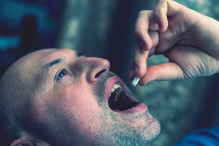 Extreme closeup man face taking white pill, mouth view swallowing pills, illness. man take...